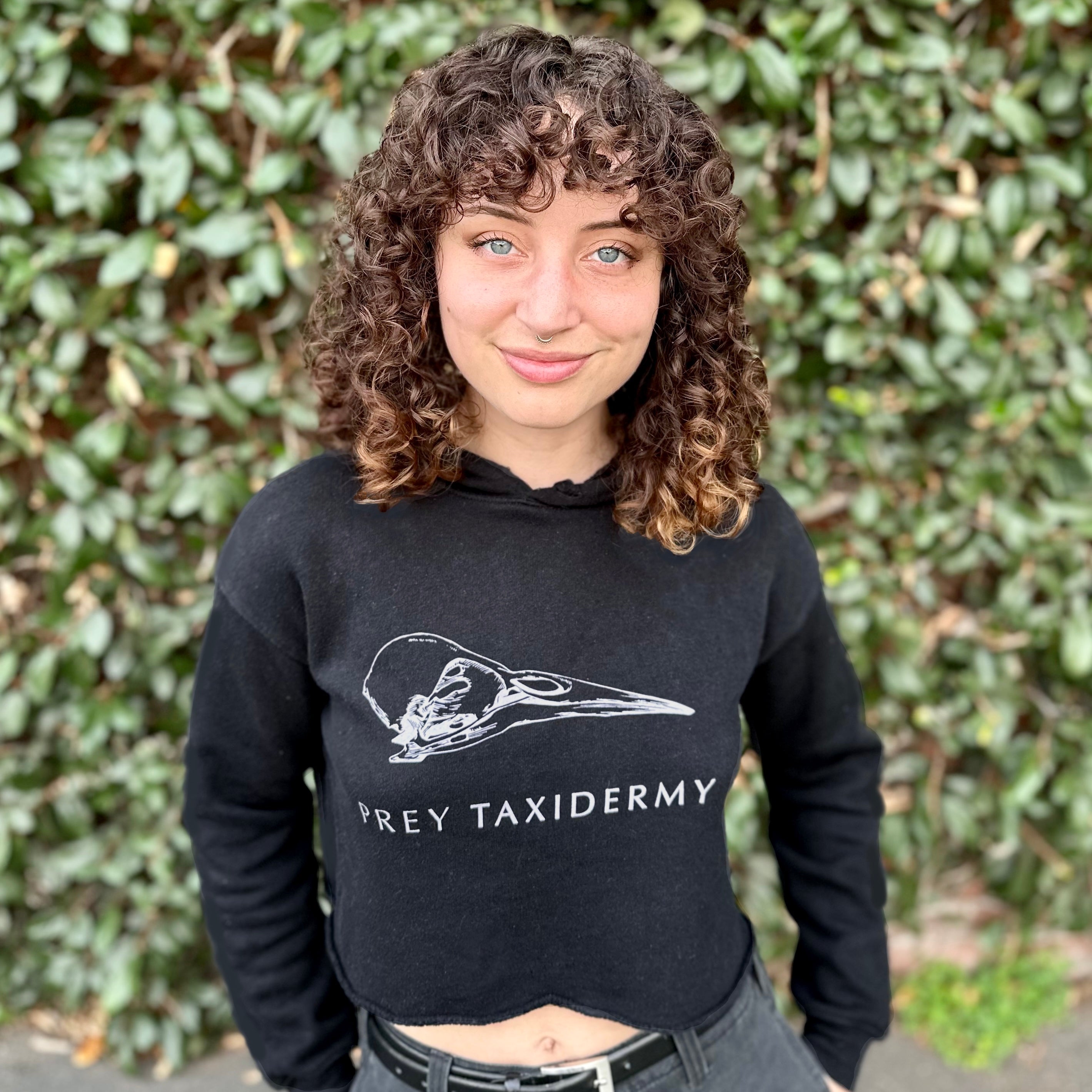 Paloma Strong, Studio Manager at Prey Taxidermy, wearing the black cropped hoodie. Black Crop Hoodie | Black Cropped Hoodie | Prey Taxidermy Hoodie | Prey Taxidermy Logo in White with Bird Skull